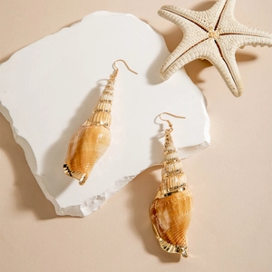Detailed close-up of natural conch shell earrings with gold plating on white stone