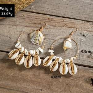 Close-up of beach style gold hoop earrings with natural shells and white turquoise beads