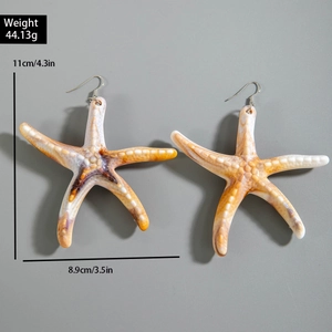 Macro view of oversized orange starfish drop earrings showing size and texture details