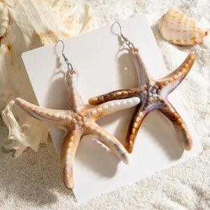 Realistic starfish drop earrings on sand background for beach vacation style