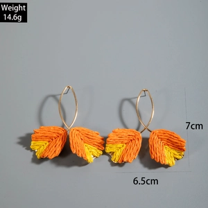 Detailed view of handmade raffia leaf earrings in orange and yellow with dimension markings