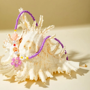 Detailed shot of handmade colorful beaded necklace with floral charms on white conch shell