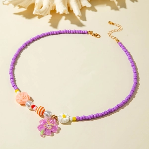 Detail of beaded starfish necklace with purple flower pendant and floral accents