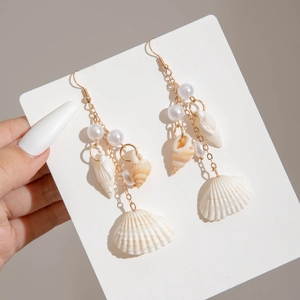 Detail of seashell drop earrings with gold chain and white pearls for beach style