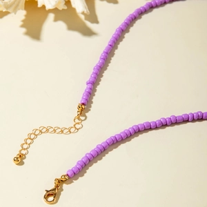 Detail view of purple seed bead necklace with gold lobster clasp and starfish shell accent