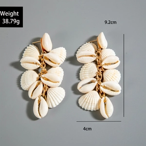 Detail showing shell drop earrings with 9.2cm length and 38.79g weight on gray background
