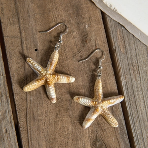 Macro detail of starfish earrings with realistic resin texture on dark wood background