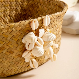 Detail of beach-style drop earrings with natural white seashells and golden hooks