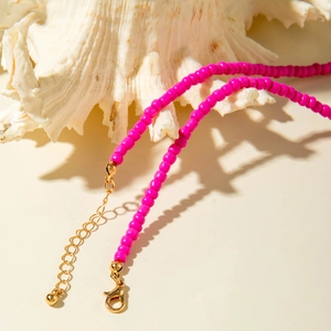 Detail of hot pink beaded necklace with gold lobster clasp and adjustable metal chain