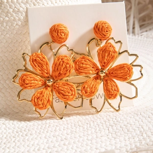 Bohemian leaf-shaped raffia earrings with gold frames displayed on a summer sun hat