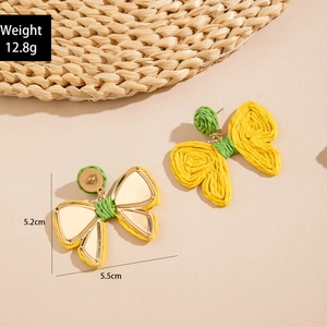 Close-up of bohemian butterfly-shaped raffia earrings with yellow and green woven texture