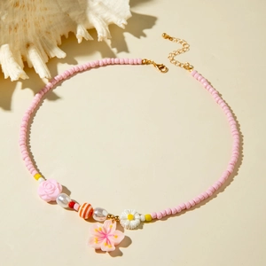 Detailed shot of pink beaded ocean necklace with shell accents and cherry blossom pendant