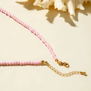 Detailed view of pink beaded necklace with gold lobster clasp and adjustable extension chain
