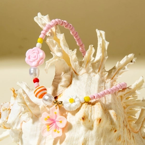 Close-up of pink beaded beach necklace with shell, flower charms and cherry blossom pendant