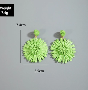 Macro detail of leaf-shaped raffia earrings showing size and handmade woven texture