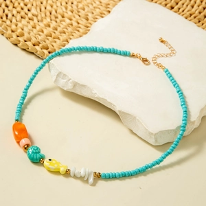 Detail of beaded necklace featuring turquoise beads, seashell charms and colorful fish pendant