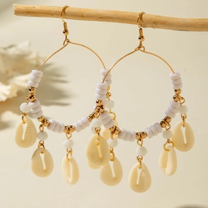 Detail of beach style gold hoop earrings with white beads and natural conch shells