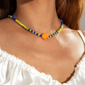 Close-up of colorful seed bead necklace with orange fish pendant on a model