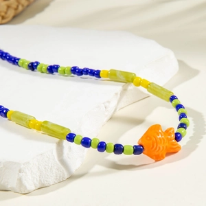 Macro detail of summer beach beaded necklace featuring a vibrant orange fish pendant