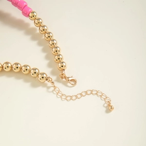 Detail of beaded necklace with gold lobster clasp, pink beads and adjustable chain extension