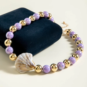 Close-up of beach ocean necklace with purple pearls and shell pendant on blue velvet