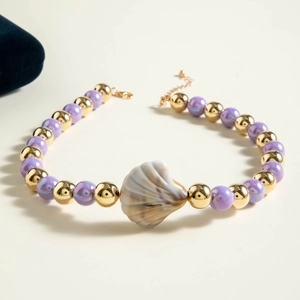 Detail of beaded necklace featuring purple beads and marble textured shell pendant