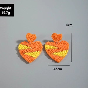 Detailed view of handmade heart-shaped orange beaded earrings with size and weight marks