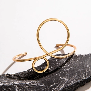 Minimalist gold hollow geometric open bangle bracelet on dark grey stone display