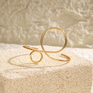 Close-up of minimalist gold hollow geometric bracelet on textured stone, modern art style