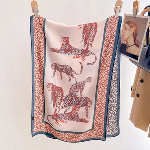 Elegant leopard print silk scarf in pink and orange displayed with a stylish trench coat