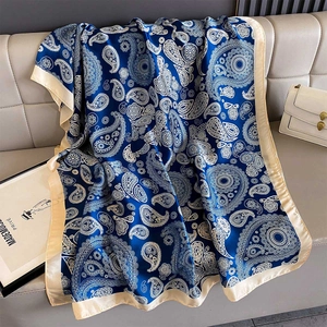 Macro detail of navy blue paisley print scarf with silky texture on leather sofa