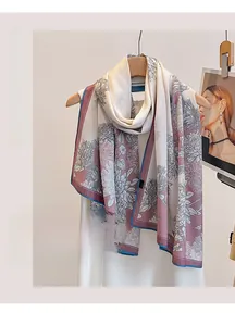 Close-up of floral print summer shawl with blue hem on wooden hanger and minimalist background