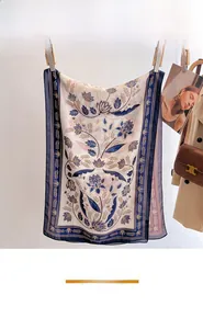 Detail view of a luxury floral print silk scarf styled with a classic trench coat and bag