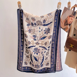 Elegant floral silk scarf in beige and blue draped with luxury lifestyle accessories