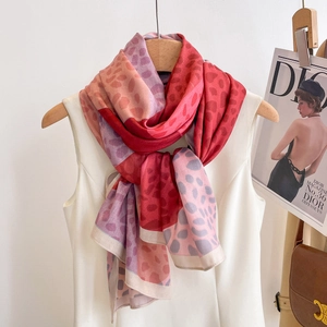 Long silk-feel scarf with red and pink leopard print pattern hanging on a wood hanger