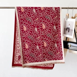 Close-up of red paisley print scarf with white border and elegant tassel fringe detail