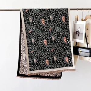 Detail of elegant black paisley scarf with soft tassels and intricate pink patterns