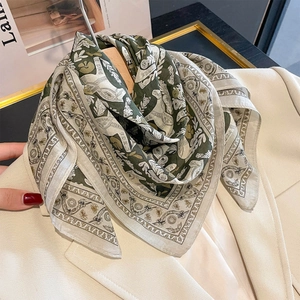Vintage olive green silk square scarf with horse print on a beige blazer