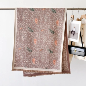 Detail of elegant paisley print scarf with fringe edges in soft earthy tones