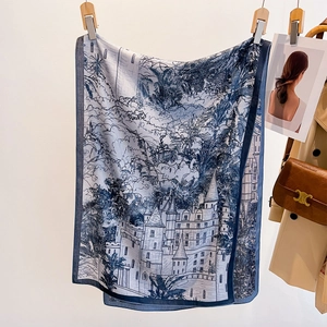 Blue architectural print silk scarf with castle motif, styled on a modern coat outfit