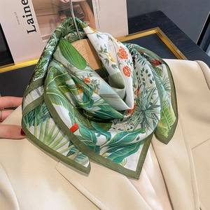 Floral print silk scarf in green and orange hanging on a beige blazer stylish accessory