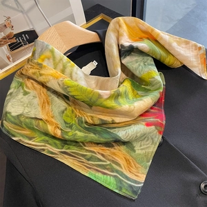 Carré de soie à imprimé floral artistique posé sur un blazer noir et un cintre en bois