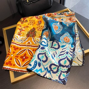 Bohemian paisley print silk scarf with vibrant geometric patterns displayed on a gold rack
