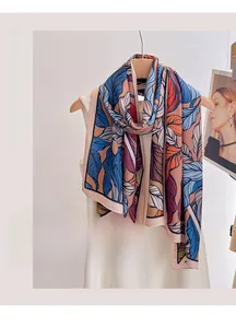 Detail of vibrant tropical leaf print on a stylish summer silk scarf with beach sun protection