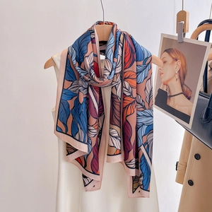 Chic botanical print beach scarf displayed on a wooden hanger with a summer dress
