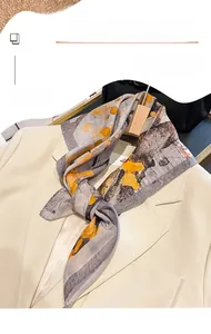 Nahaufnahme eines Seidenschals mit abstraktem Druck, elegant an einen Blazer geknotet