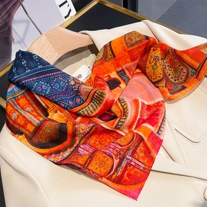Bohemian patterned satin scarf draped on a white blazer showing vibrant orange and red prints