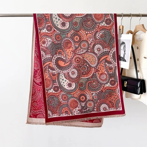 Détail du châle à motif cachemire rouge avec franges délicates sur un cintre élégant