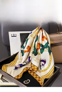 Close-up of luxury silk scarf with chain print and twill texture on a brown tray