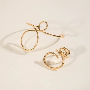 Minimalist gold coiled wire jewelry detail featuring glossy bangles and rings